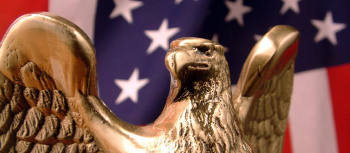 A golden eagle in front of the american flag