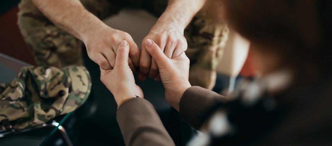 military man holding hands in support