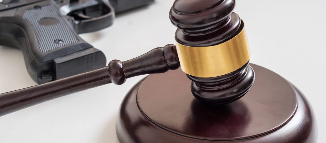 Gavel in front of a pistol. Gun laws and legislation concept.