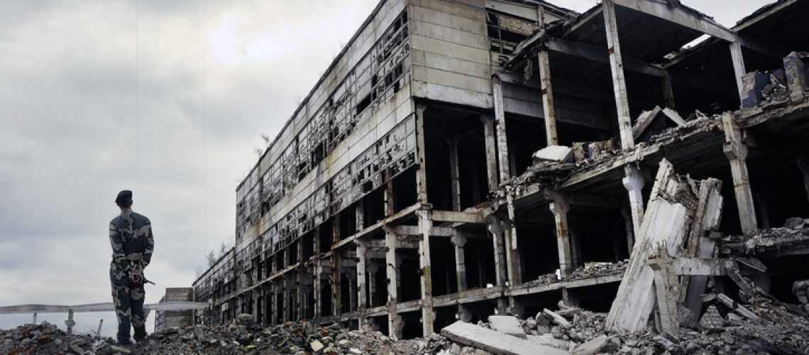 oldier in military uniform stands on the ruins